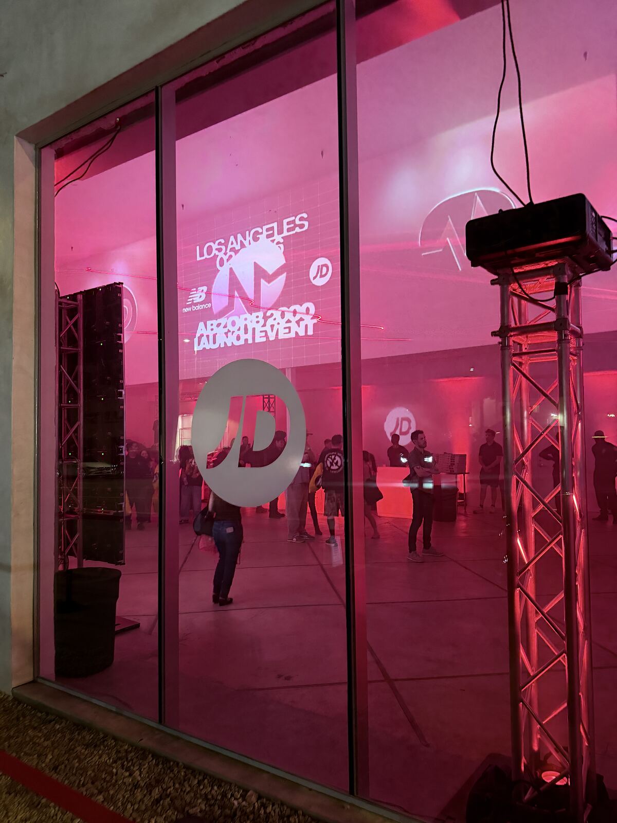 Indoor event booth with magenta lighting and professional stage rigging infrastructure