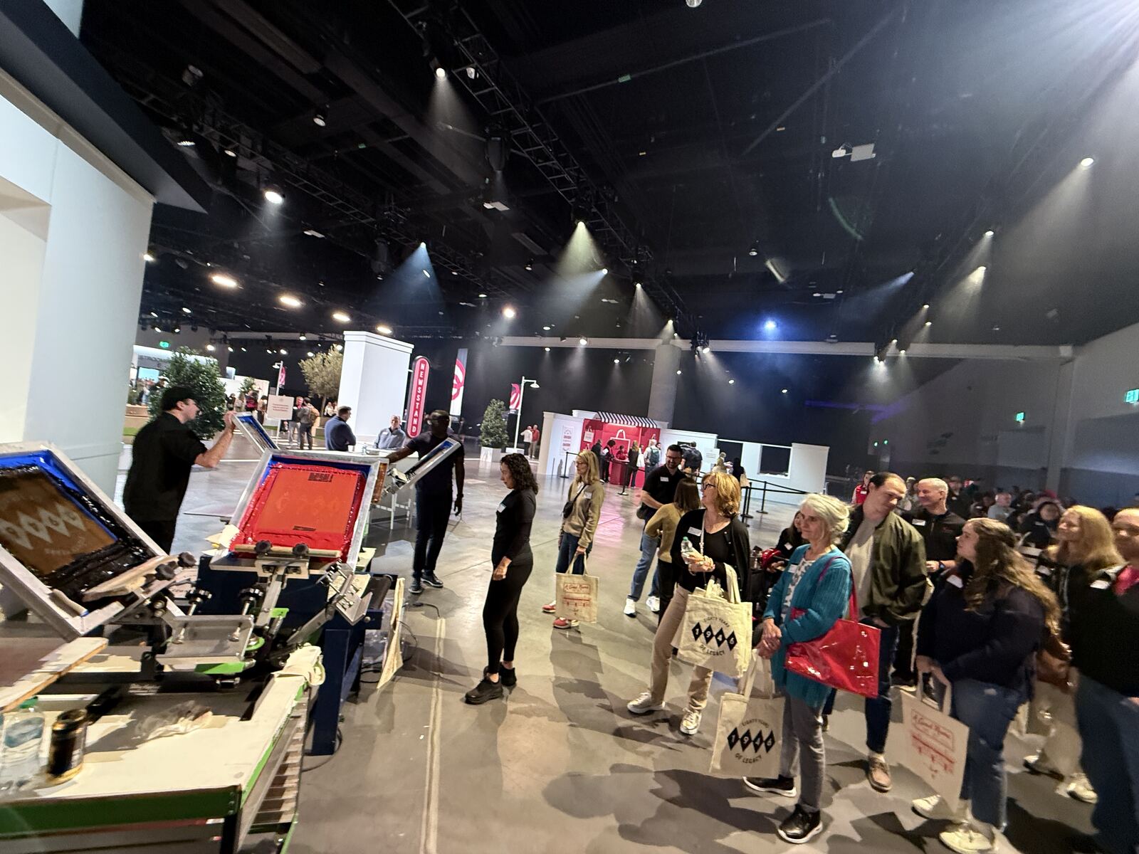 Team of seven staff members standing behind an event booth with printing equipment and branded merchandise